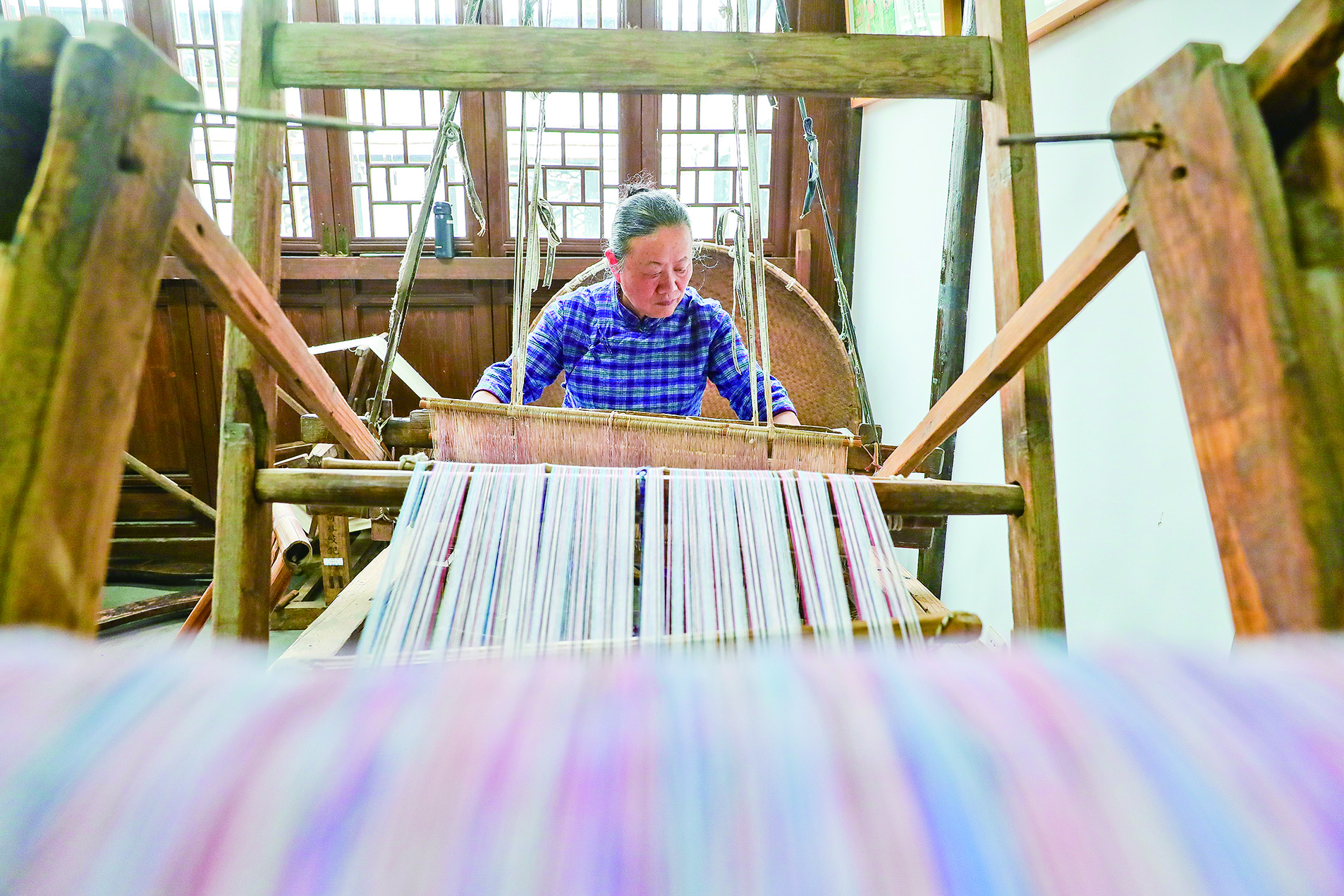 一名民间布艺制作人在馆内纺纱织布